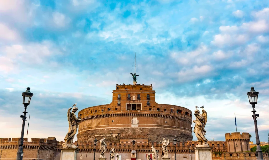 Castel Sant'Angelo et statues d'anges sur le Pont Sant'Angelo à Rome au coucher du soleil avec ciel nuageux